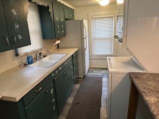 kitchen featuring fridge, sink, and green cabinetry