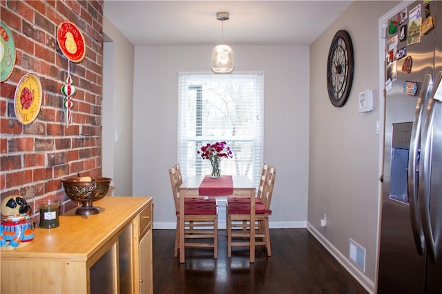 dining space with brick wall, dark wood-type flooring, and a wealth of natural light