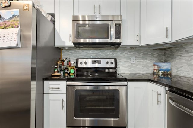 kitchen with tasteful backsplash, dark stone countertops, white cabinets, and appliances with stainless steel finishes