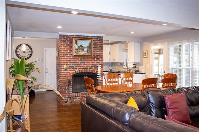 living room with dark hardwood / wood-style flooring, sink, and a fireplace