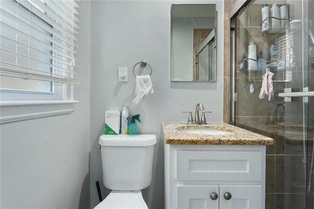 bathroom with vanity, a shower with door, and toilet