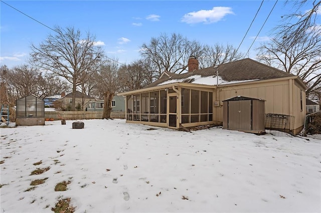 snow covered property featuring an outdoor structure and a sunroom