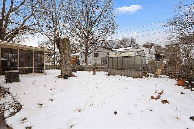 yard covered in snow featuring a sunroom