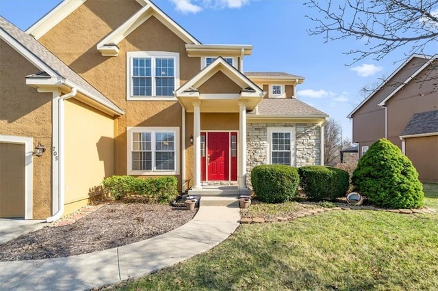 view of front facade with a front yard, a garage, stone siding, and stucco siding