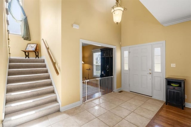 entrance foyer featuring tile patterned flooring, crown molding, stairs, and baseboards