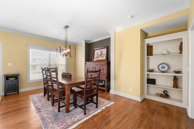 dining area with ornamental molding, built in shelves, an inviting chandelier, and wood finished floors