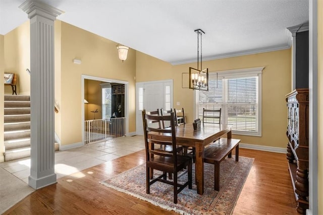 dining area featuring stairs, wood finished floors, and ornate columns