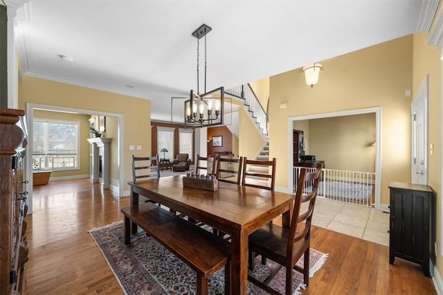 dining space featuring crown molding, stairway, wood finished floors, and baseboards