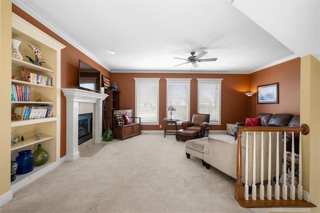 living room featuring a tiled fireplace, carpet flooring, crown molding, and a ceiling fan