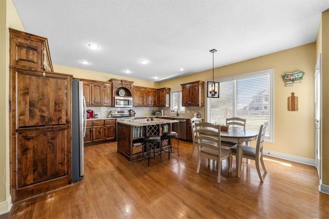 dining area with dark wood-type flooring, recessed lighting, baseboards, and a textured ceiling