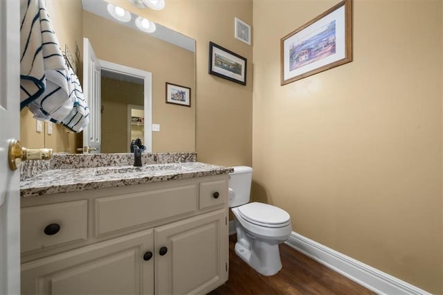 half bath featuring visible vents, baseboards, toilet, and vanity