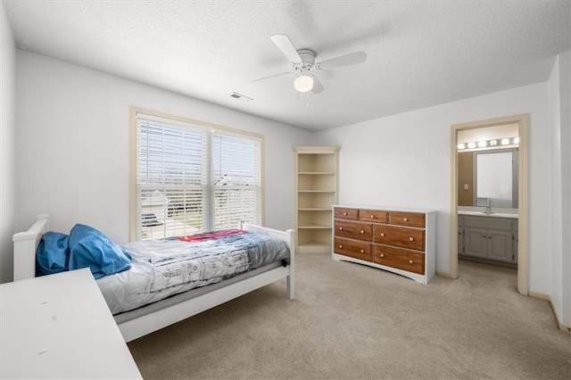 bedroom with ceiling fan, light carpet, ensuite bathroom, a textured ceiling, and a sink