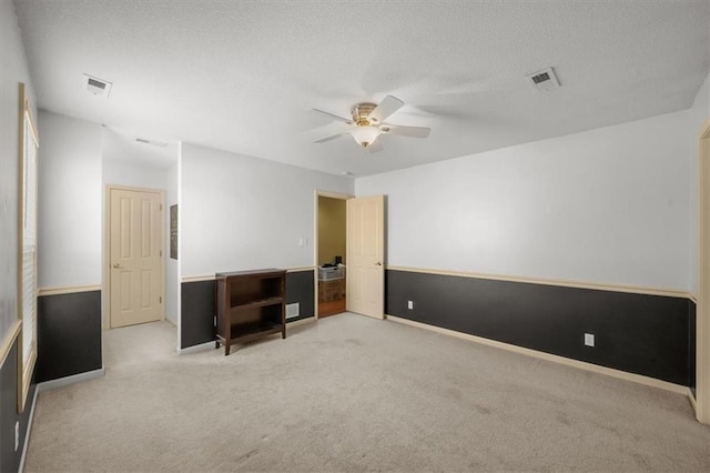 unfurnished room with visible vents, carpet floors, a textured ceiling, and ceiling fan