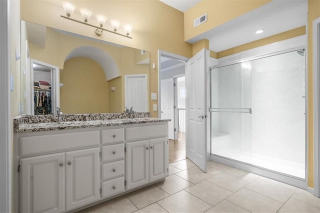 full bath featuring visible vents, a sink, a shower stall, tile patterned flooring, and double vanity