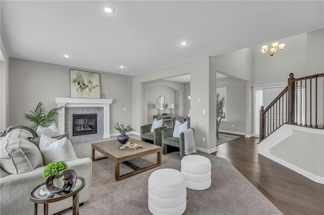 living room with dark wood-style floors, recessed lighting, a chandelier, a tile fireplace, and baseboards