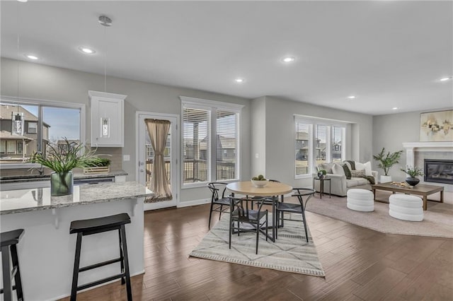 dining area with recessed lighting, baseboards, dark wood finished floors, and a glass covered fireplace