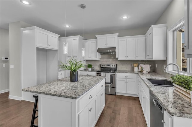 kitchen featuring white cabinets, a center island, hanging light fixtures, stainless steel appliances, and a sink