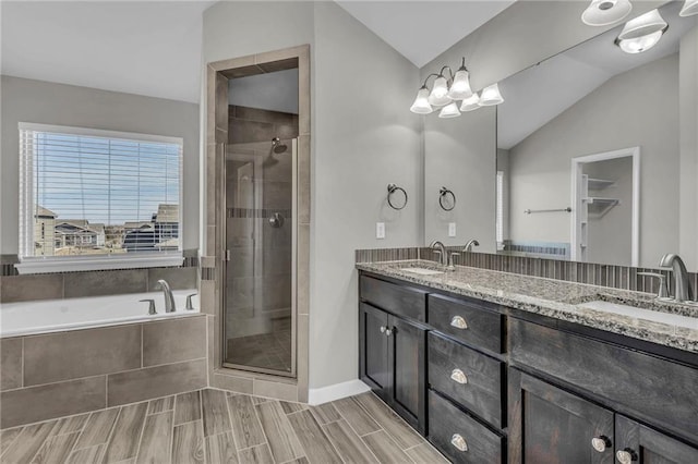 bathroom featuring vaulted ceiling, a sink, a shower stall, and double vanity