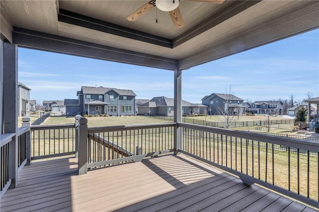 deck featuring ceiling fan, a residential view, a lawn, and a fenced backyard