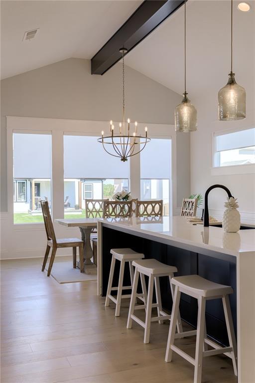 kitchen featuring vaulted ceiling with beams, light countertops, visible vents, and a healthy amount of sunlight