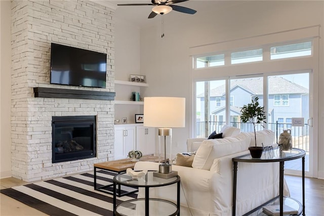 living room with ceiling fan, a fireplace, and wood finished floors