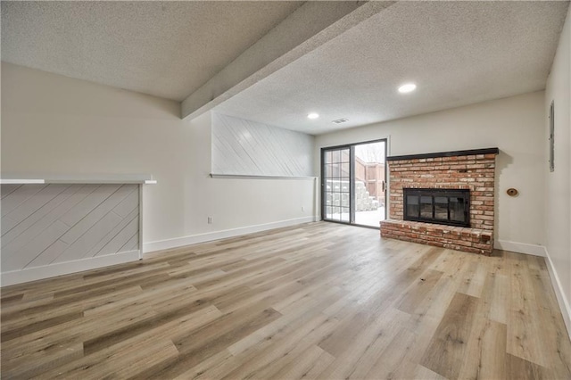 unfurnished living room featuring a fireplace, light hardwood / wood-style flooring, and a textured ceiling