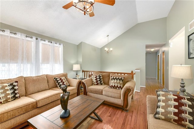 living area with ceiling fan with notable chandelier, lofted ceiling, wood finished floors, and a textured ceiling