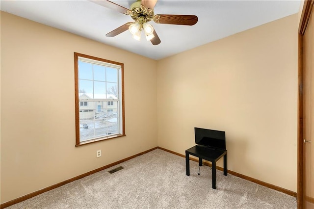 carpeted spare room featuring visible vents, baseboards, and a ceiling fan