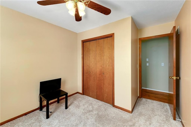 carpeted bedroom with a closet, baseboards, and a ceiling fan