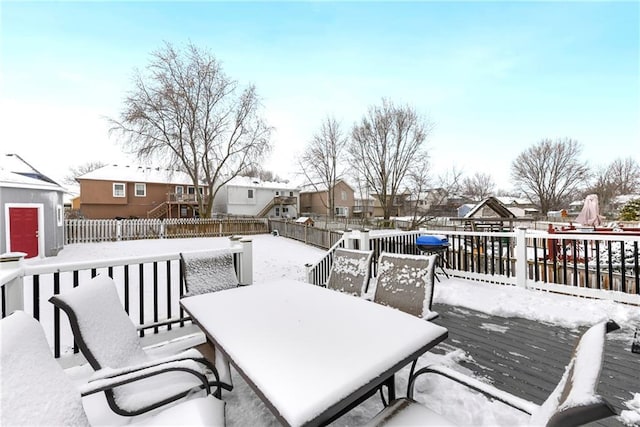 snow covered deck featuring a residential view, a fenced backyard, and outdoor dining space