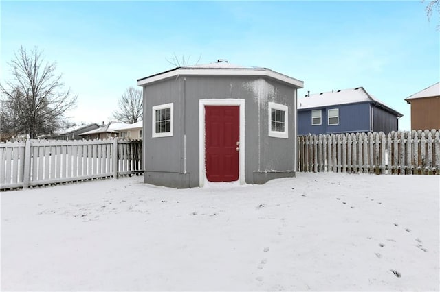 snow covered structure with an outbuilding and a fenced backyard