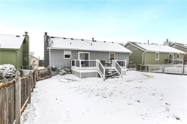 snow covered rear of property with a wooden deck and a fenced backyard