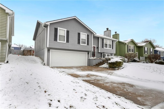 bi-level home featuring a garage, a residential view, a chimney, and fence