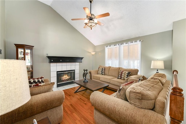 living room with a fireplace, wood finished floors, a textured ceiling, high vaulted ceiling, and a ceiling fan