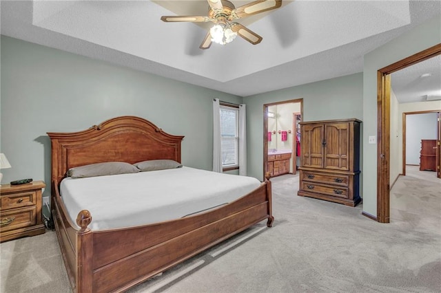 carpeted bedroom with connected bathroom, ceiling fan, and a tray ceiling