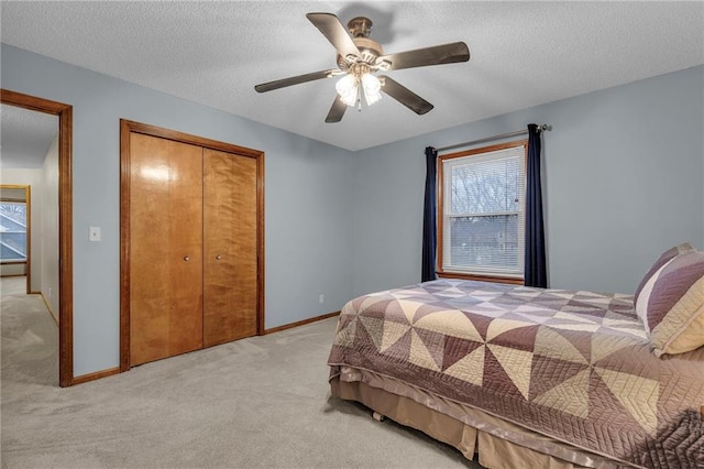 carpeted bedroom featuring ceiling fan, a textured ceiling, and a closet