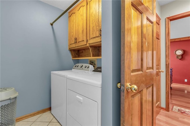 clothes washing area with cabinets, washing machine and dryer, and light tile patterned floors