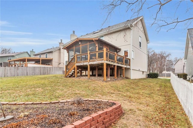 back of house with a wooden deck, a sunroom, and a lawn