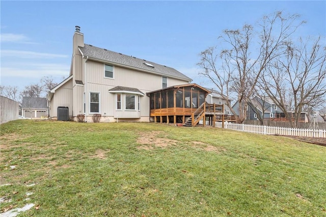 rear view of property featuring central AC, a sunroom, and a lawn