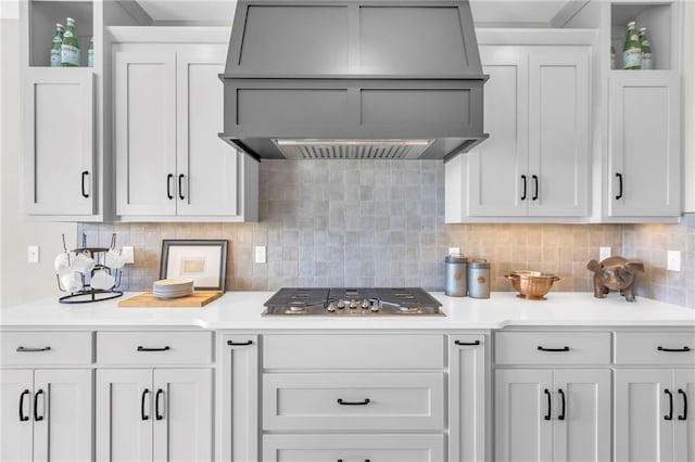 kitchen featuring custom range hood, white cabinets, stainless steel gas cooktop, and decorative backsplash