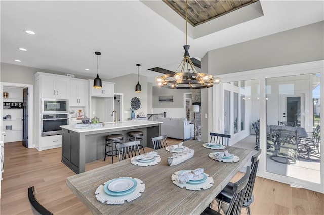 dining room with sink, light hardwood / wood-style flooring, and a notable chandelier