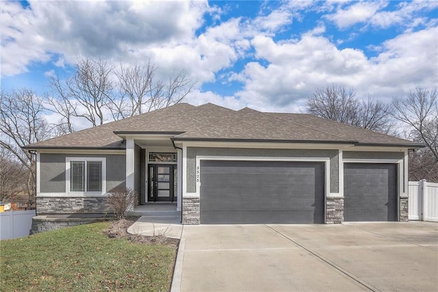 view of front of house with a garage, concrete driveway, stone siding, fence, and stucco siding