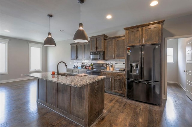 kitchen featuring a center island with sink, dark wood-type flooring, a sink, light stone countertops, and black appliances