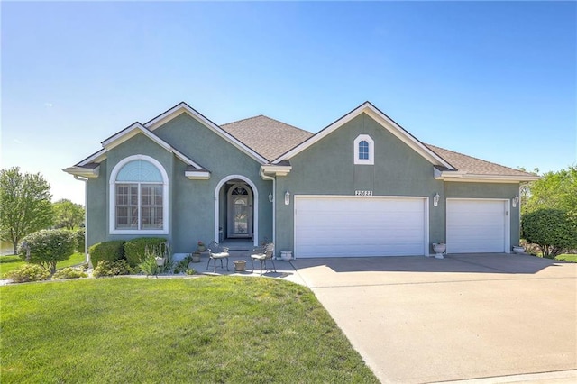 ranch-style home featuring driveway, a front yard, an attached garage, and stucco siding