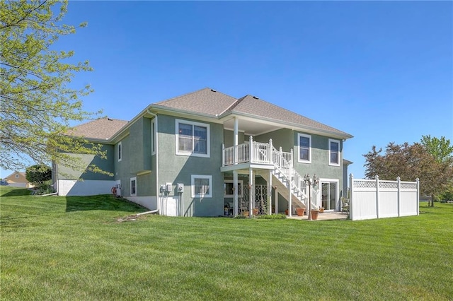 back of property featuring a yard, stairs, and stucco siding