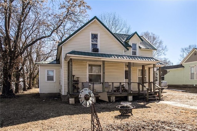 view of front of home with covered porch, a fire pit, and metal roof