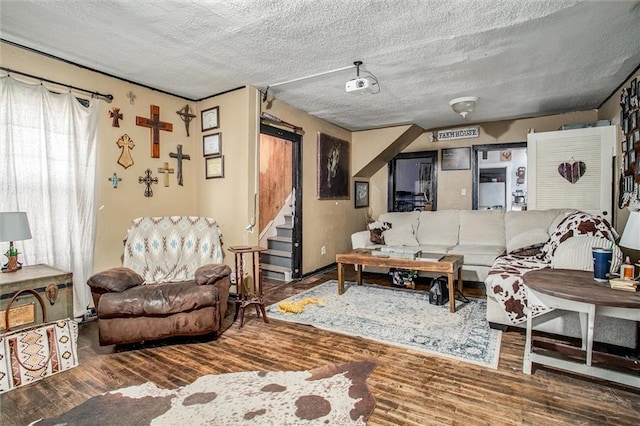 living area with stairway, a textured ceiling, and wood finished floors