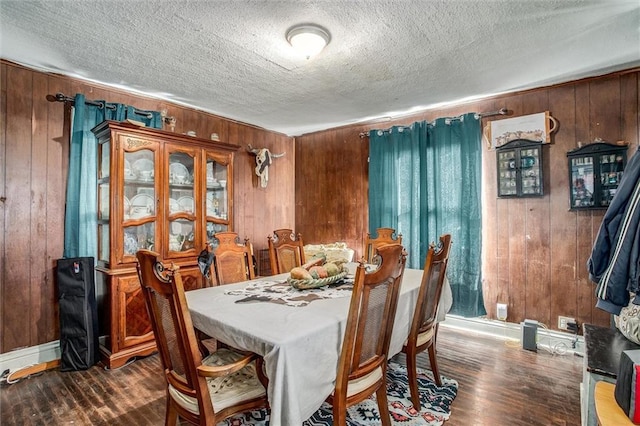 dining space featuring wood walls, a textured ceiling, and dark wood-style flooring