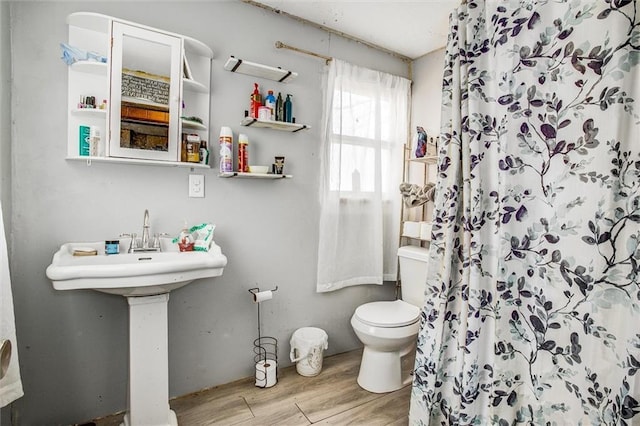 full bath featuring toilet, a shower stall, and wood finished floors