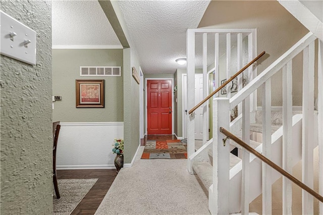 entrance foyer with baseboards, visible vents, dark wood finished floors, a textured wall, and a textured ceiling